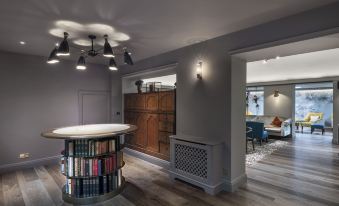 a cozy living room with hardwood floors , a fireplace , and a bookshelf filled with books at Angel Hotel