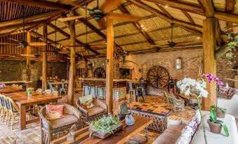 a cozy living room with wooden furniture , including couches , chairs , and a dining table , under a large wooden ceiling at Hacienda la Danesa
