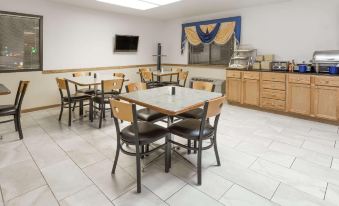a dining area with several tables and chairs , along with a tv mounted on the wall at Days Inn by Wyndham Stoughton WI.