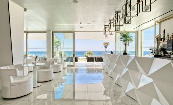 a modern hotel lobby with white walls , large windows offering views of the ocean , and multiple seating areas at Ivi Mare - Designed for Adults by Louis Hotels