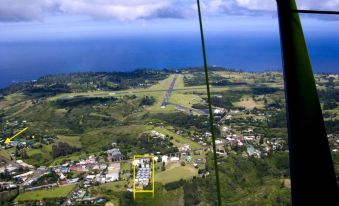 a bird 's eye view of a green valley with a white building and a blue and yellow label at Aloha Apartments