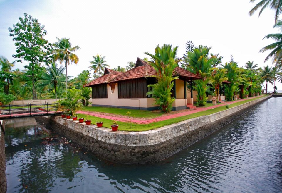 a house with a red roof is situated on the edge of a body of water , surrounded by palm trees at Paradise Resorts