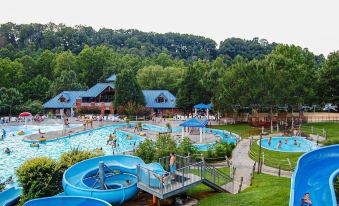 a large outdoor pool with blue water and a wooden deck , surrounded by trees and buildings at General Morgan Inn