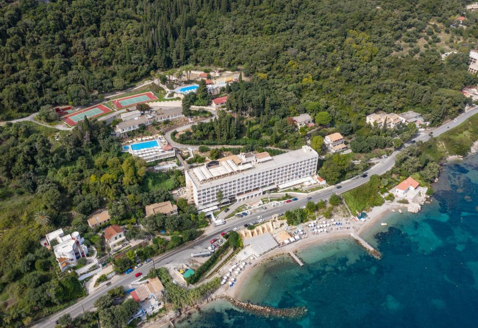 aerial view of a resort surrounded by trees , with a large building in the background at Louis Ionian Sun