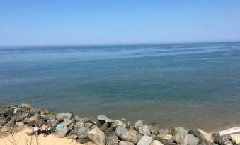 a serene beach scene with a rocky shoreline , clear blue water , and people enjoying the view at Primrose Cottage