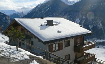 a snow - covered house on top of a mountain , with a view of the surrounding landscape at Eva