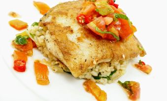 a white plate with a piece of fried fish on top , accompanied by rice and vegetables at Discovery Inn