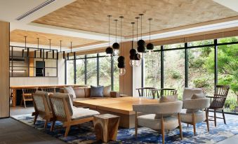 a dining room with a large wooden dining table surrounded by chairs , and pendant lights hanging from the ceiling at Fairfield by Marriott Mie Kumano Kodo Mihama