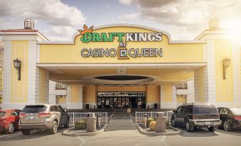 the entrance to a casino with cars parked in front and a large sign above at Casino Queen Hotel