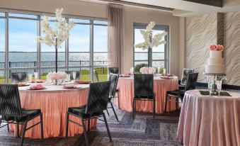 a room with several tables set up for a formal event , featuring pink tablecloths and black chairs at Aloft Ocean City