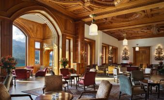 a large , elegant hotel lobby with wooden paneling , high ceilings , and multiple chairs arranged in a comfortable seating area at Badrutt's Palace Hotel St Moritz
