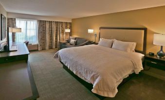 a large bed with white linens is in a hotel room next to a window at Hampton Inn Billings