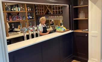 a woman standing behind a bar , preparing drinks for customers at a restaurant or bar at Loftsome Bridge Hotel