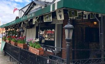 a black and white building with a green awning , surrounded by flowers and a street lamp at The Fox & Hounds