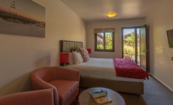 a hotel room with a bed , couch , and coffee table , as well as a window overlooking the outdoors at The Park Hotel Ruapehu