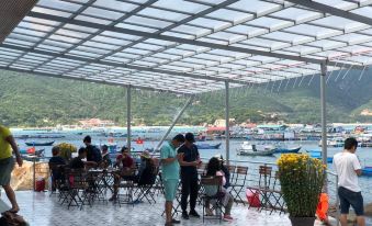 a group of people gathered on a patio overlooking a body of water , enjoying their time together at The Sea Rock Binh Hung