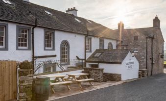 "a white building with a sign that says "" misty waters "" and a picnic table in front of it" at The Greyhound Hotel