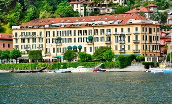 a large hotel situated on the edge of a body of water , with several boats docked nearby at Grand Hotel Menaggio