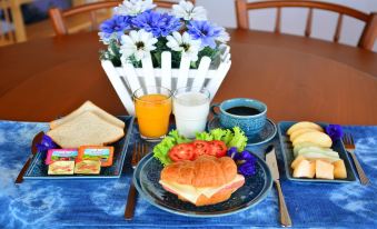 a breakfast table with a variety of food items , including sandwiches , fruit , and juice at The Indigo House Phrae