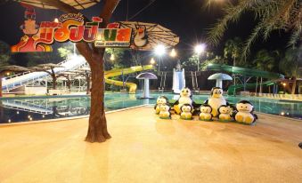 a group of penguins standing in front of a water park with umbrellas and lights at Nonghan Grand Hotel and Resort