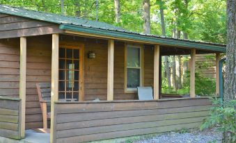 a small wooden cabin surrounded by trees , with a green roof and a sign on the front porch at Lost Lodge Resort