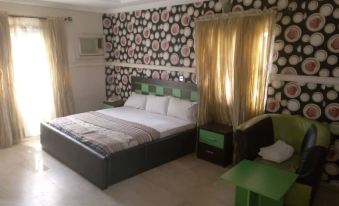 a bedroom with a large bed , white and black polka dot wallpaper , and a green table at Brentwood Hotel