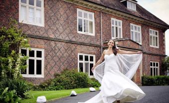 a woman in a white dress is posing for a photo in front of a brick building at Mercure Goulburn