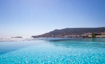 a serene swimming pool with clear blue water and a beautiful view of mountains in the background at Konstantinos Palace