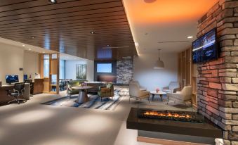 a modern living room with wooden ceiling , white walls , and a fireplace , as well as comfortable seating arrangements at Fairfield by Marriott Edmonton International Airport