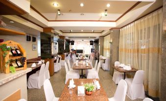 a large dining room with white tables and chairs , some of which are covered in white tablecloths at Chaipat Hotel