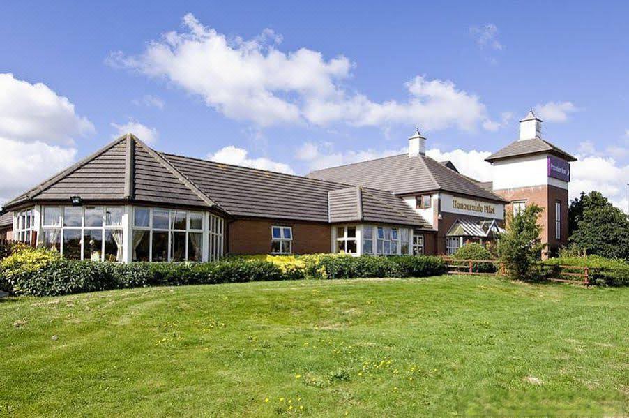 a large , two - story house with a brown roof and white trim , surrounded by green grass and trees at Premier Inn Gillingham Business Park