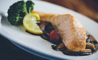 a plate of food on a dining table , with a piece of salmon and broccoli at Kellys Inn
