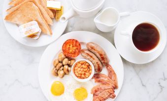 a plate of breakfast food , including eggs , bacon , and sausage , is accompanied by a cup of coffee at Best Western Plus London Croydon Aparthotel