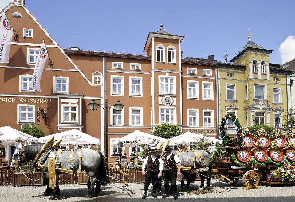 a horse - drawn carriage with several people riding on it is parked in front of a building at Akzent Hotel Aufkirchen