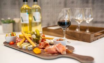 a wooden cutting board with a variety of meats , cheeses , and crackers , accompanied by a glass of wine at Campanile Laval Nord