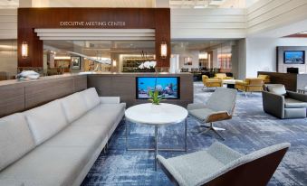 a hotel lobby with a white couch , chairs , and a tv mounted on the wall at Hyatt Regency Dulles
