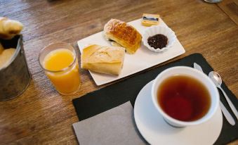 a dining table with a cup of tea , a plate of pastries , and a glass of orange juice at Sofi Hotel