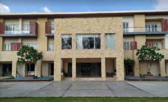 a modern , beige - colored building with large windows and balconies , surrounded by trees and a well - maintained lawn at Ritz Resort