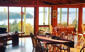 a room with wooden furniture and large windows overlooking a body of water , providing a scenic view at Bluff House Inn