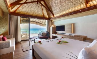 a luxurious bedroom with a large bed , a tv , and a view of the ocean at Le Bora Bora by Pearl Resorts