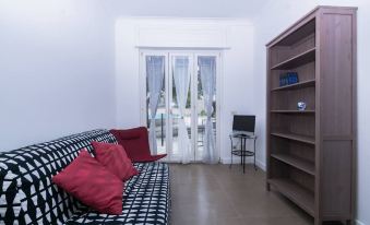a living room with a black and white checkered couch , a television , and a bookshelf at YourHome - Villa Sorrento