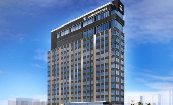 a modern , multi - story building with a black exterior and large windows , under a blue sky with clouds at Candeo Hotels Omiya