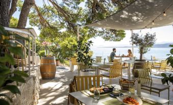 an outdoor dining area with several tables and chairs , where people are enjoying their meals at Tui Blue Makarska