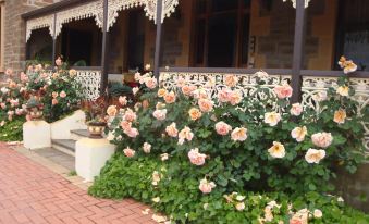 a house with a brick walkway and a row of pink roses in front of it at Copper House