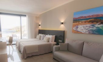 a bedroom with a large bed , a couch , and a painting of a desert landscape on the wall at Hotel Dos Playas