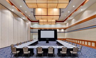 a large conference room with a long table , chairs , and a projector screen in the center at DoubleTree by Hilton Phoenix Tempe