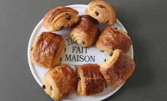 a white plate with a variety of pastries , including croissants and buns , arranged in a circle at La Grande Maison