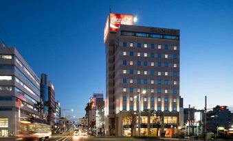 a tall building with a coca - cola sign on top is lit up at night in a city at Kochi Hotel