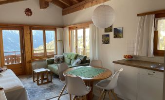 a modern living room and dining area with wooden furniture , a green chair , and large windows overlooking the mountains at Eva