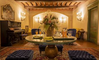 a well - decorated living room with a round dining table surrounded by chairs , a piano , and a couch at Hotel Boccaccio